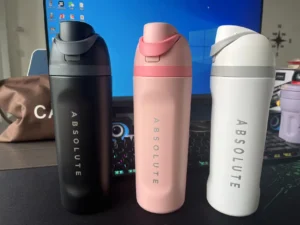 where are Owala water bottles made – custom Owala bottles in black, pink, and white colors displayed on a desk